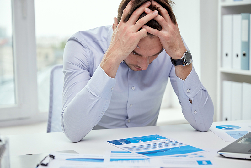 man who is at work who is very stressed about paperwork in front of him